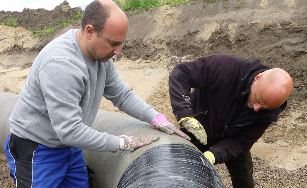 Field installation team applying PrimaTape water activated cement tape on pipeline